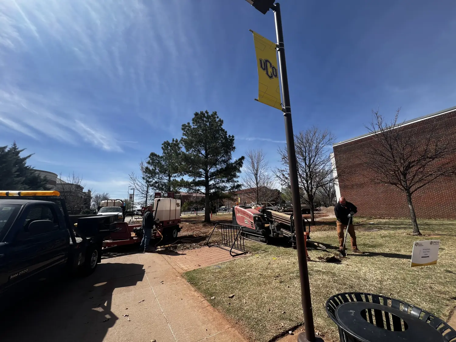 Trinity Boring Solutions directional drill rig and crew working a street beside an Oklahoma commercial building