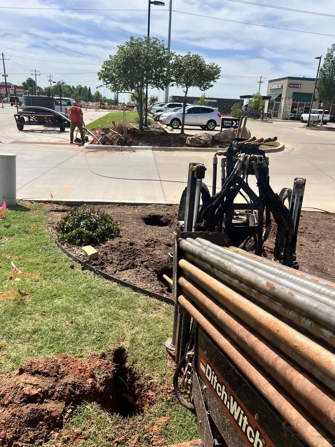 Ditch Witch directional drill rig with a loaded drill rod rack at an Oklahoma commercial jobsite