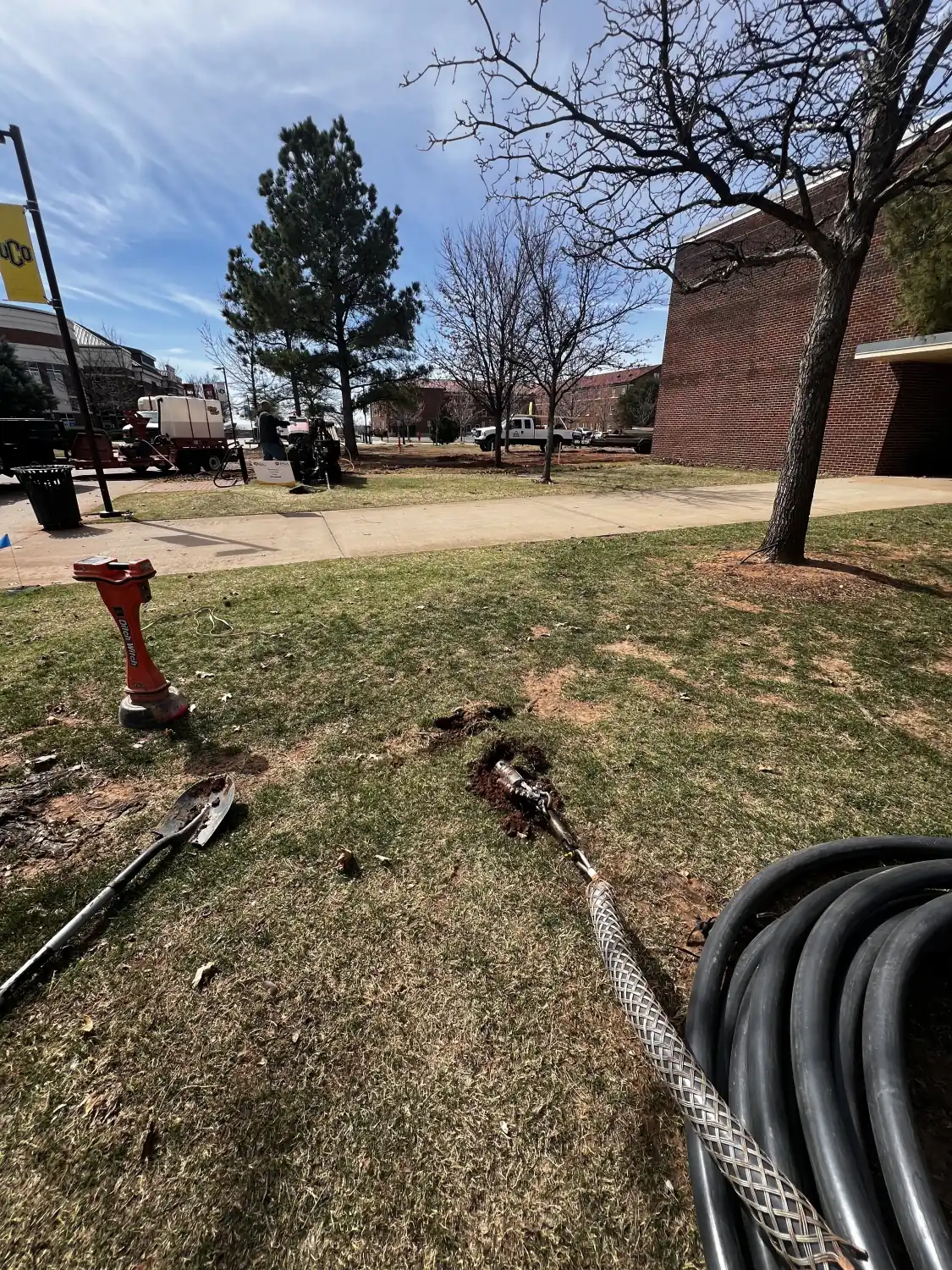 Black HDPE conduit with a pulling grip staged on a lawn along a completed bore path in Oklahoma