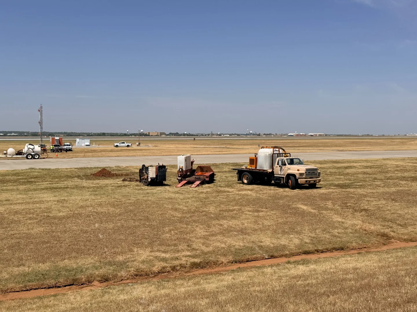 Hydrovac truck and boring equipment staged beside an airport taxiway for utility daylighting in Oklahoma City